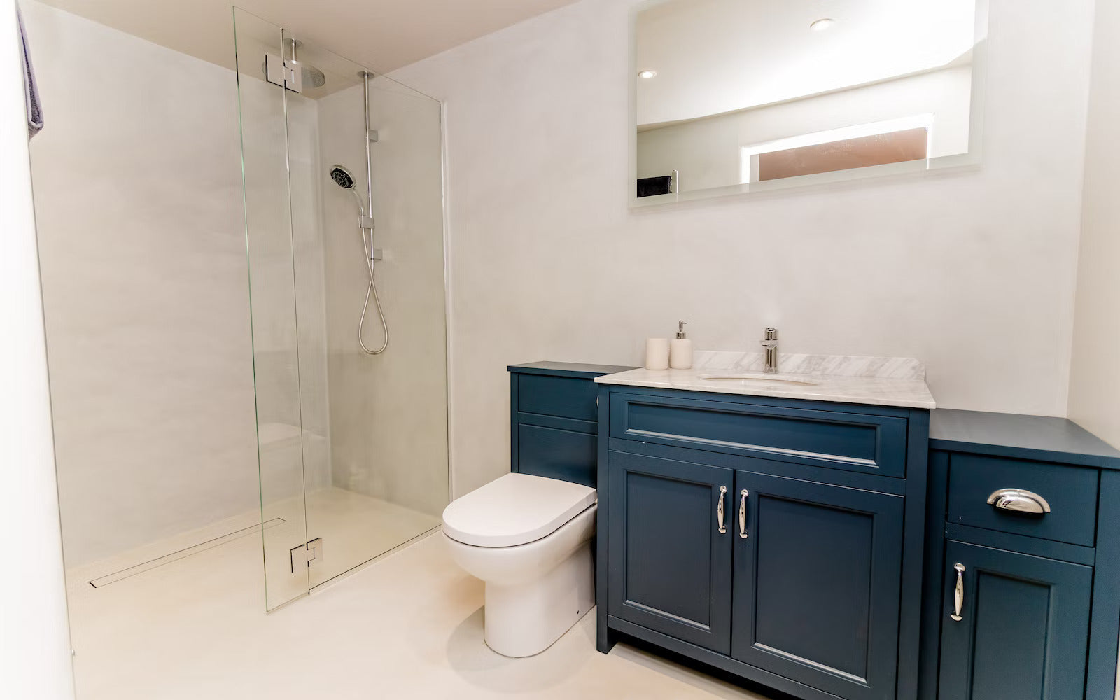 Bathroom with blue vanity, white toilet, and shower area.